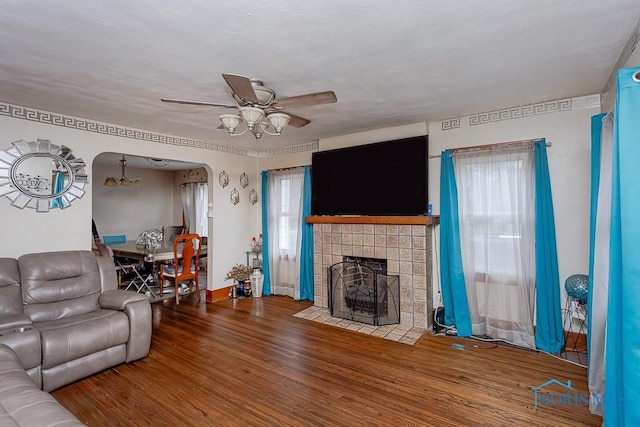 living room with ceiling fan, wood-type flooring, and a fireplace