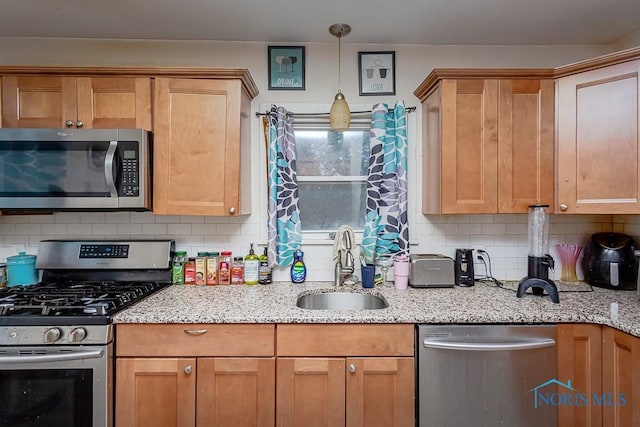 kitchen featuring light stone counters, sink, decorative backsplash, and appliances with stainless steel finishes