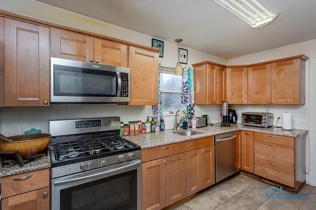 kitchen featuring light tile patterned flooring, sink, light stone counters, tasteful backsplash, and appliances with stainless steel finishes