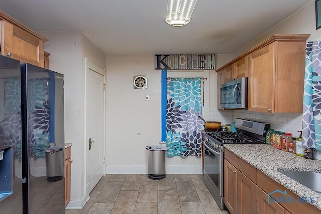 kitchen featuring light tile patterned flooring, appliances with stainless steel finishes, sink, decorative backsplash, and light stone countertops