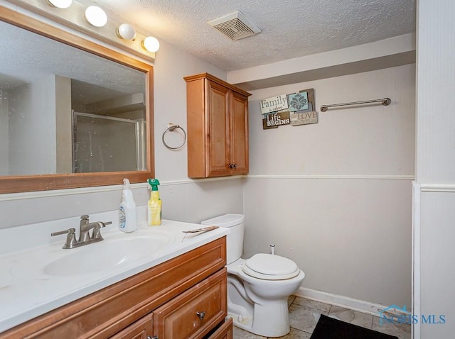 bathroom featuring toilet, a shower with shower door, a textured ceiling, vanity, and tile patterned flooring