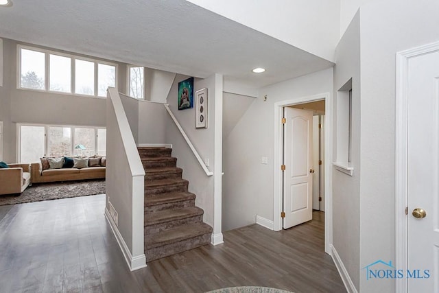 stairway featuring a towering ceiling and hardwood / wood-style floors