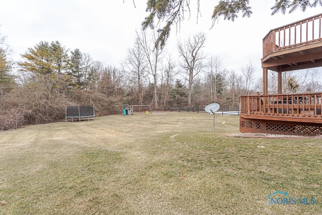 view of yard featuring a trampoline, a wooden deck, and a playground