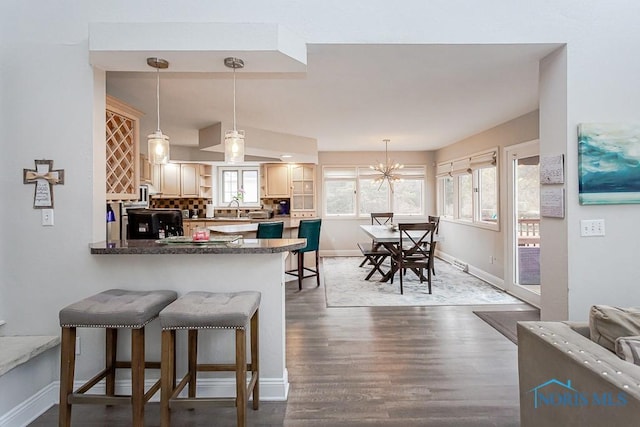 kitchen with dark hardwood / wood-style floors, pendant lighting, decorative backsplash, and kitchen peninsula