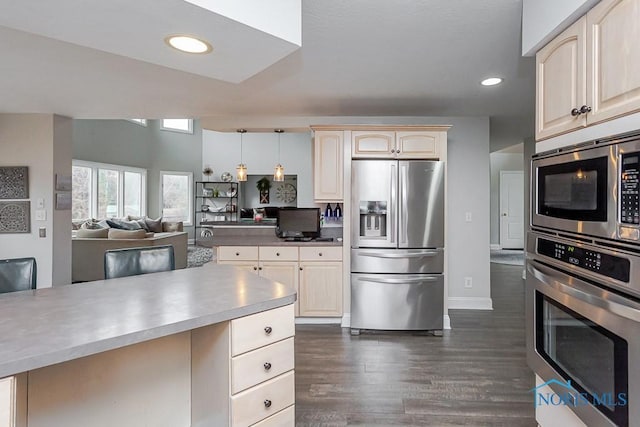 kitchen with cream cabinetry, appliances with stainless steel finishes, dark hardwood / wood-style flooring, and decorative light fixtures