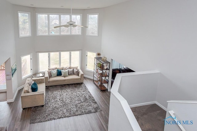 living room with hardwood / wood-style flooring, a towering ceiling, and ceiling fan