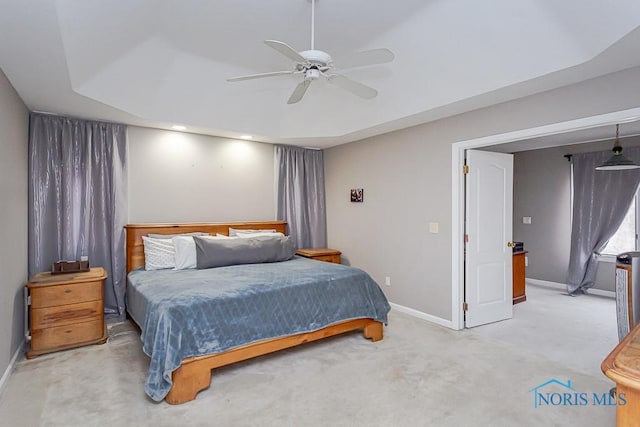 bedroom with light carpet, a tray ceiling, and ceiling fan