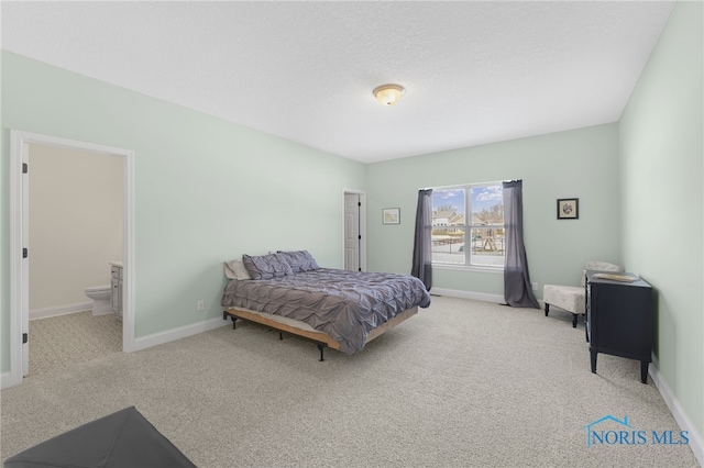 bedroom featuring light colored carpet, ensuite bathroom, and a textured ceiling