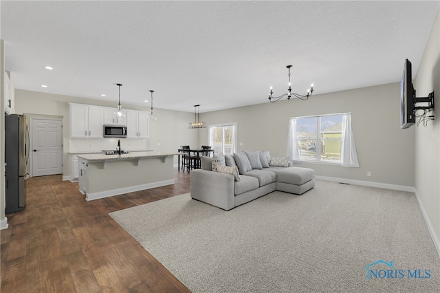 living room with dark hardwood / wood-style floors, sink, a notable chandelier, and a textured ceiling