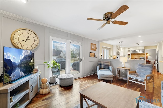 living area with hardwood / wood-style flooring, ornamental molding, and ceiling fan