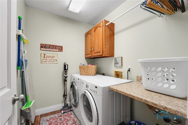 laundry room with cabinets, wood-type flooring, and washing machine and clothes dryer