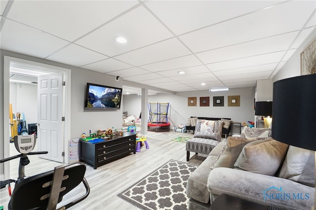 living room featuring a drop ceiling and light wood-type flooring