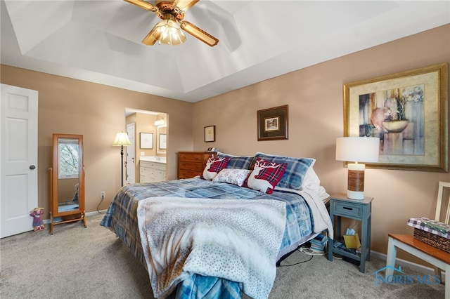 carpeted bedroom featuring ensuite bath, a raised ceiling, and ceiling fan