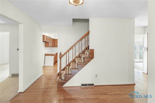 staircase with wood finished floors, visible vents, and baseboards