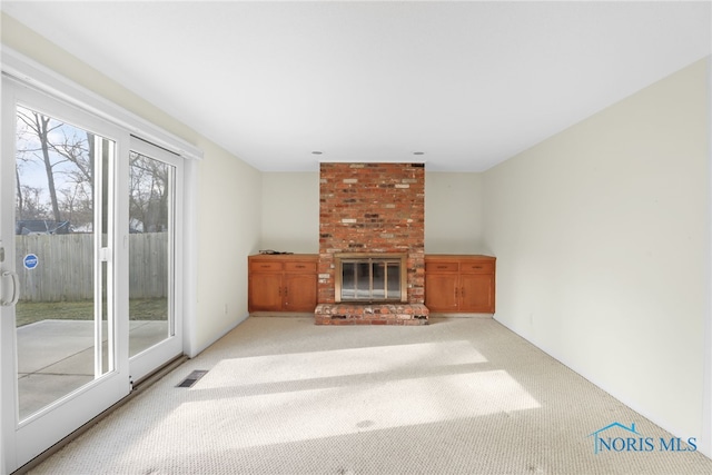 unfurnished living room with carpet flooring, a fireplace, and visible vents