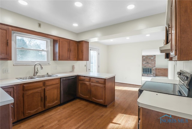 kitchen featuring dishwasher, wood finished floors, a peninsula, under cabinet range hood, and a sink