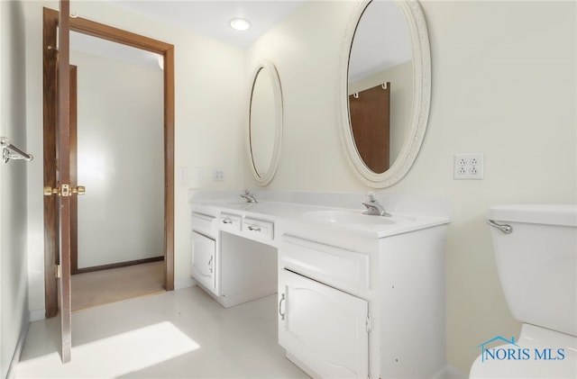 bathroom featuring double vanity, a sink, toilet, and baseboards