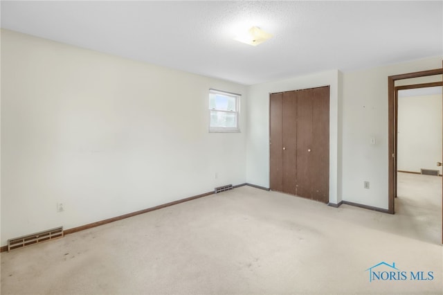 unfurnished bedroom with a closet, carpet flooring, visible vents, and baseboards