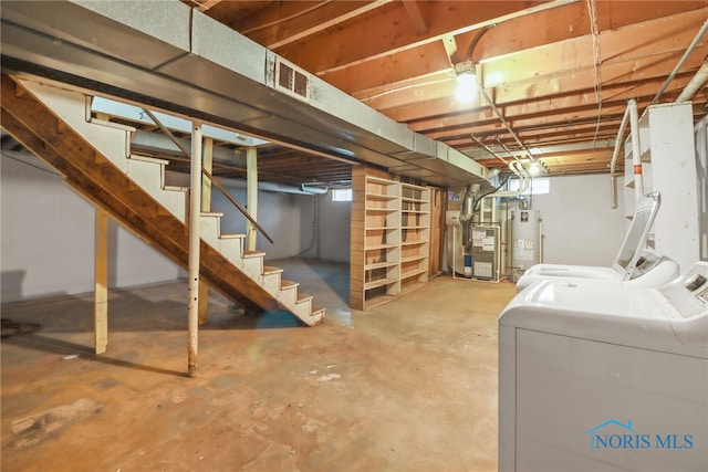 basement featuring gas water heater, heating unit, visible vents, stairway, and washer and dryer