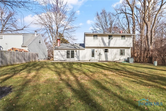 rear view of house with a patio, central AC unit, fence, a lawn, and a chimney