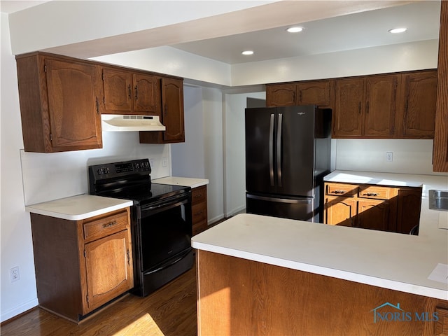 kitchen with black appliances, dark wood-style flooring, light countertops, and under cabinet range hood