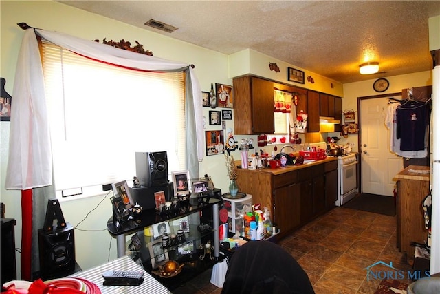 kitchen with white gas range, sink, and a textured ceiling