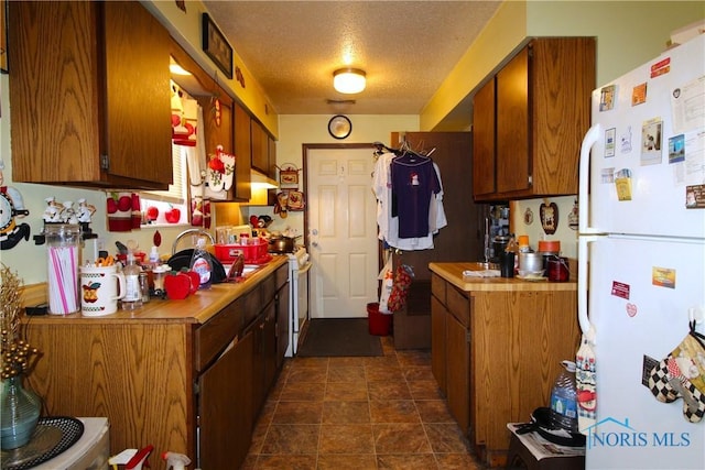 kitchen with sink, a textured ceiling, and white appliances