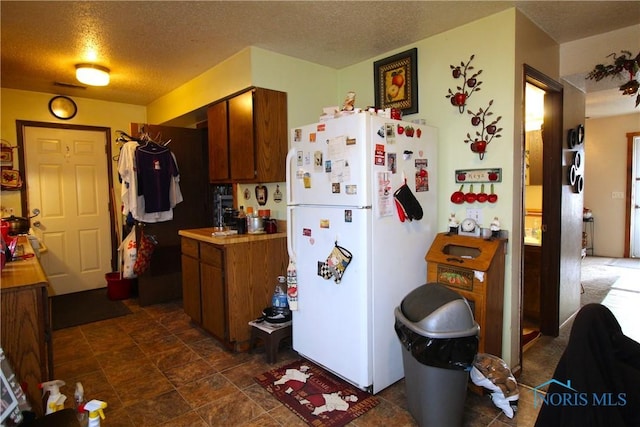 kitchen featuring white refrigerator and a textured ceiling