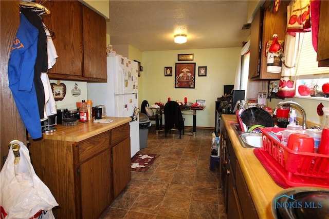 kitchen with white refrigerator, sink, and a textured ceiling