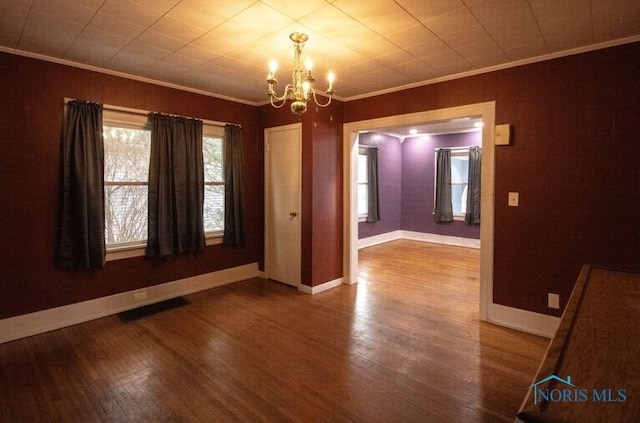 spare room featuring crown molding, hardwood / wood-style flooring, and a chandelier