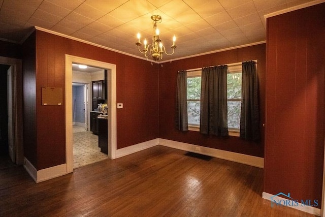 empty room with crown molding, an inviting chandelier, and dark wood-type flooring