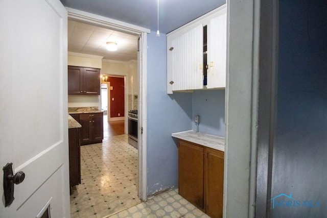 kitchen featuring stainless steel range, ornamental molding, and dark brown cabinetry