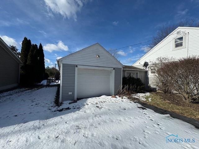 snow covered garage featuring a detached garage