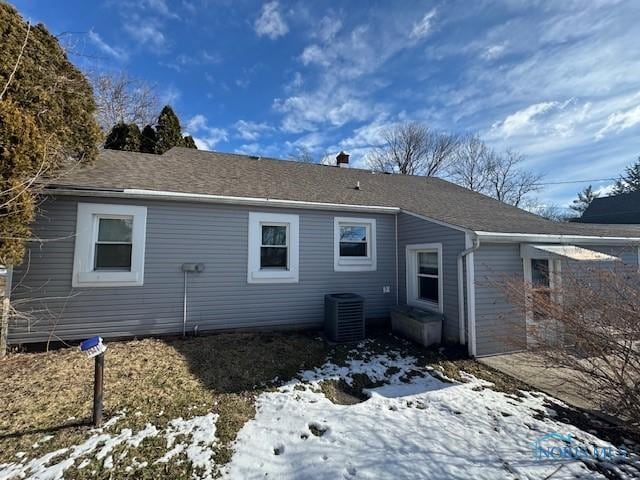 rear view of property with central AC and a shingled roof