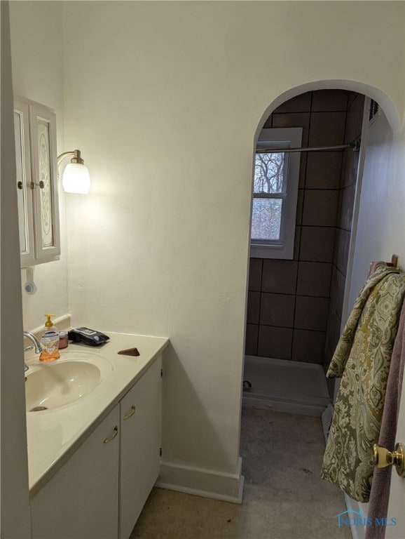 bathroom with a shower stall, vanity, and baseboards