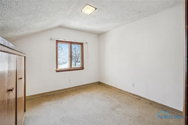 unfurnished bedroom with lofted ceiling and a textured ceiling