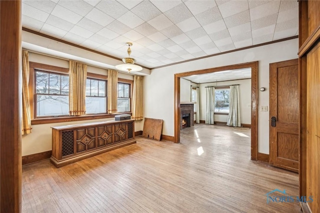 interior space with crown molding, a brick fireplace, and light wood-type flooring