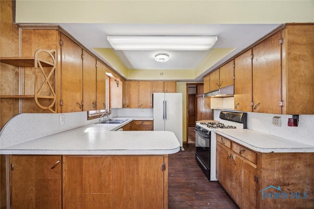 kitchen with sink, dark hardwood / wood-style floors, high quality fridge, range with gas cooktop, and kitchen peninsula