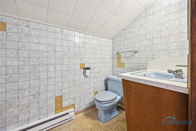 bathroom featuring lofted ceiling, toilet, tile walls, vanity, and a baseboard heating unit