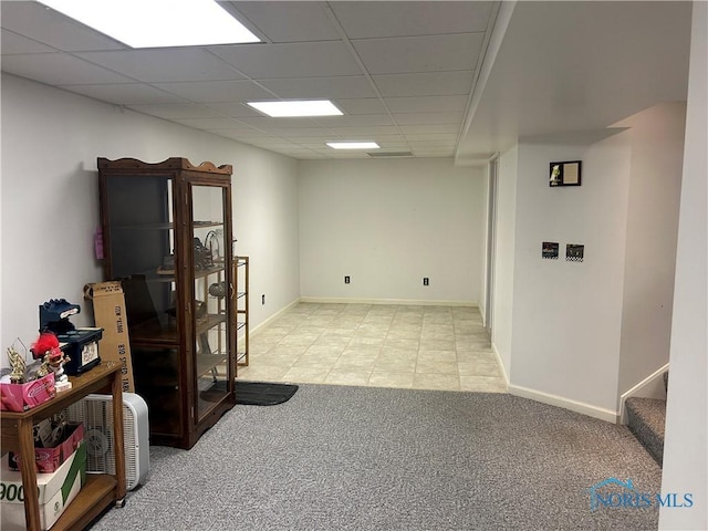 interior space with a paneled ceiling and light carpet