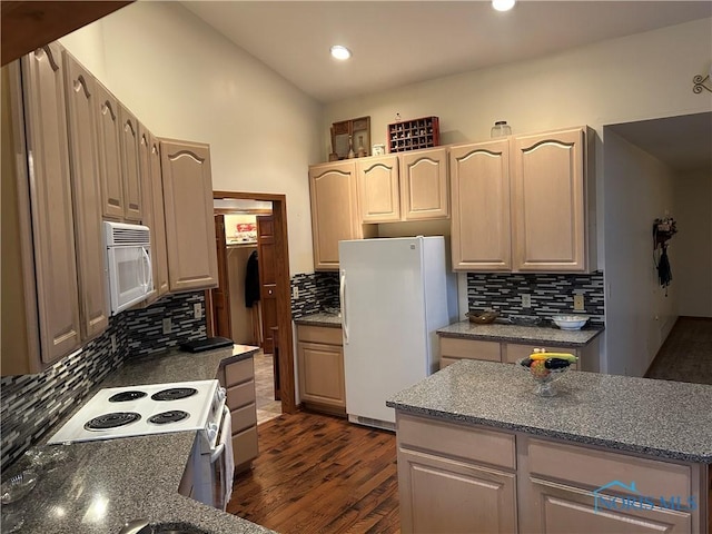 kitchen featuring dark hardwood / wood-style flooring, white appliances, vaulted ceiling, and tasteful backsplash