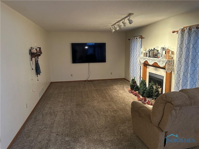 living room with a tile fireplace, rail lighting, and carpet flooring