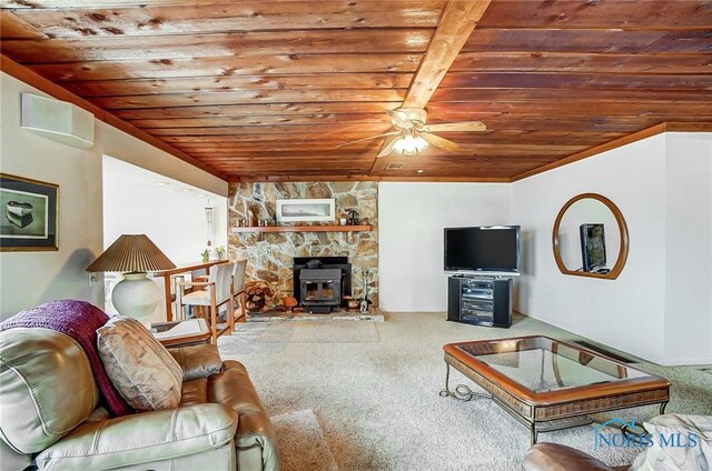 carpeted living room featuring ceiling fan, a wood stove, and wood ceiling