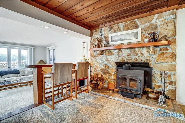 carpeted living room featuring wooden ceiling and a wood stove