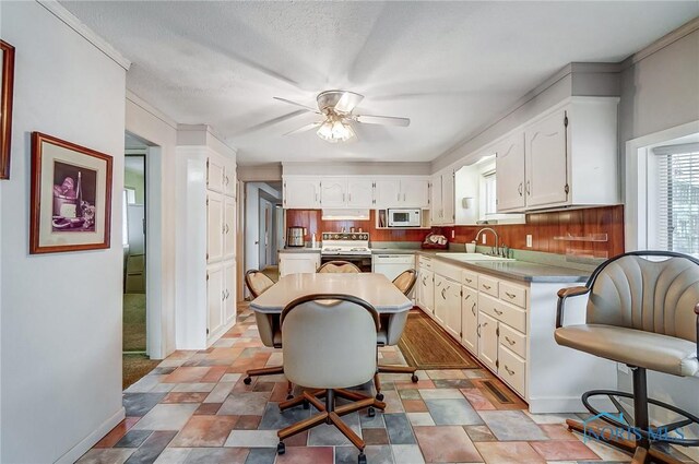 kitchen featuring a kitchen bar, sink, a kitchen island, range with electric cooktop, and ceiling fan