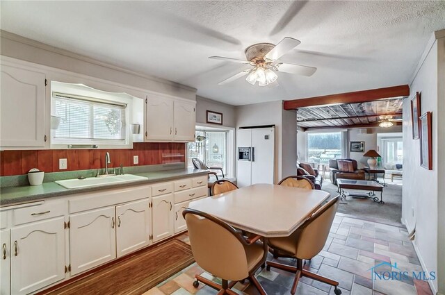 kitchen with ceiling fan, sink, a textured ceiling, and white cabinets