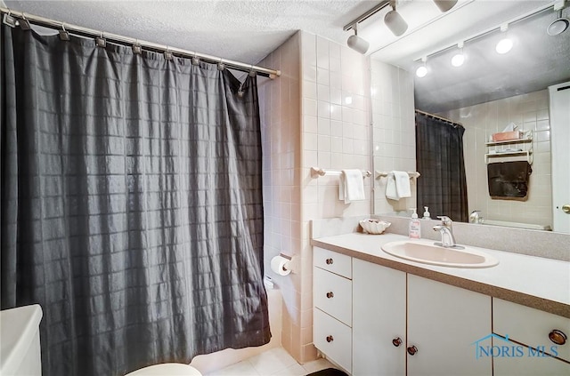 bathroom featuring tile walls, tile patterned flooring, vanity, a textured ceiling, and toilet