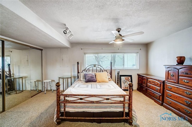 carpeted bedroom with ceiling fan, a closet, and a textured ceiling