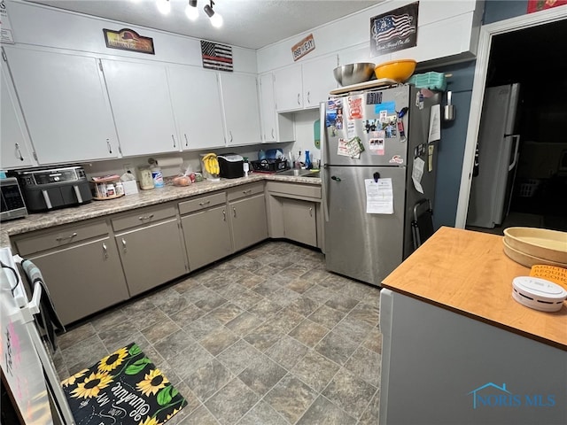 kitchen with stove, stainless steel fridge, and gray cabinets