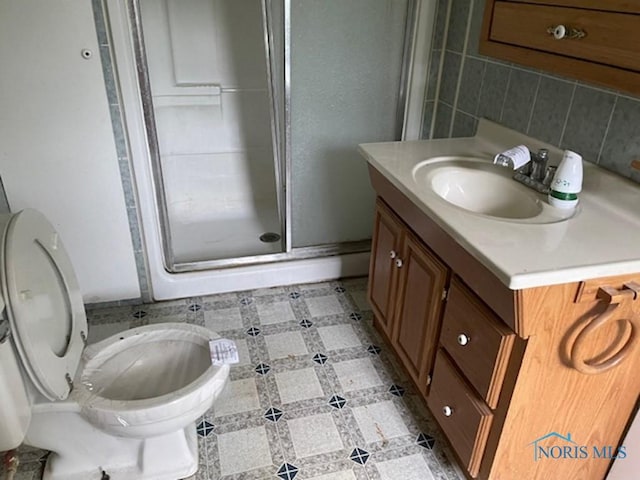 bathroom with vanity, decorative backsplash, toilet, and walk in shower